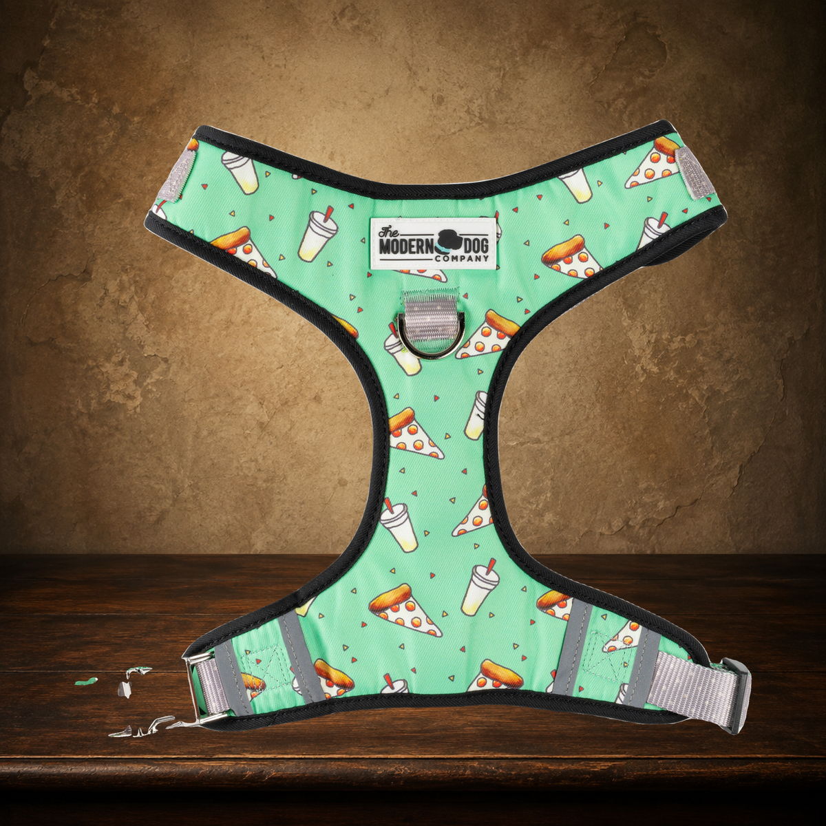 The Midnight Slice — Pizza Party Dog Harness displayed on the approved antique plaster and walnut table