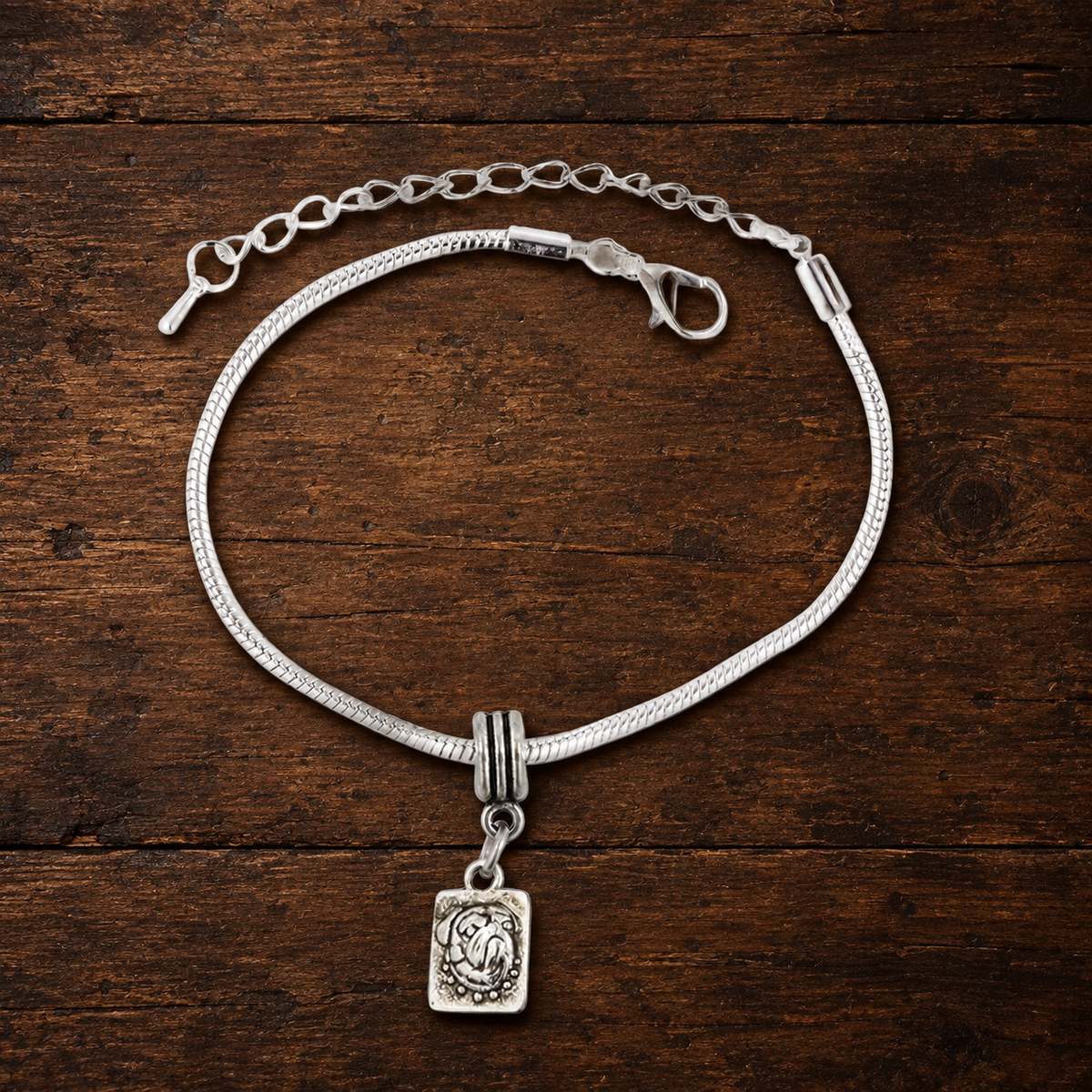 Pug charm bracelet resting on a walnut tabletop